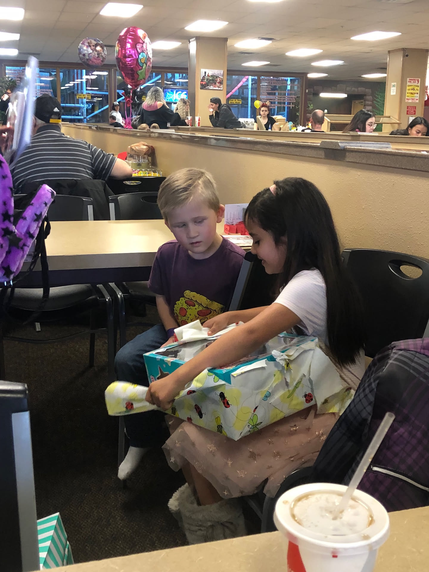 Kelbie opening her presents with her cousin sitting next to her.